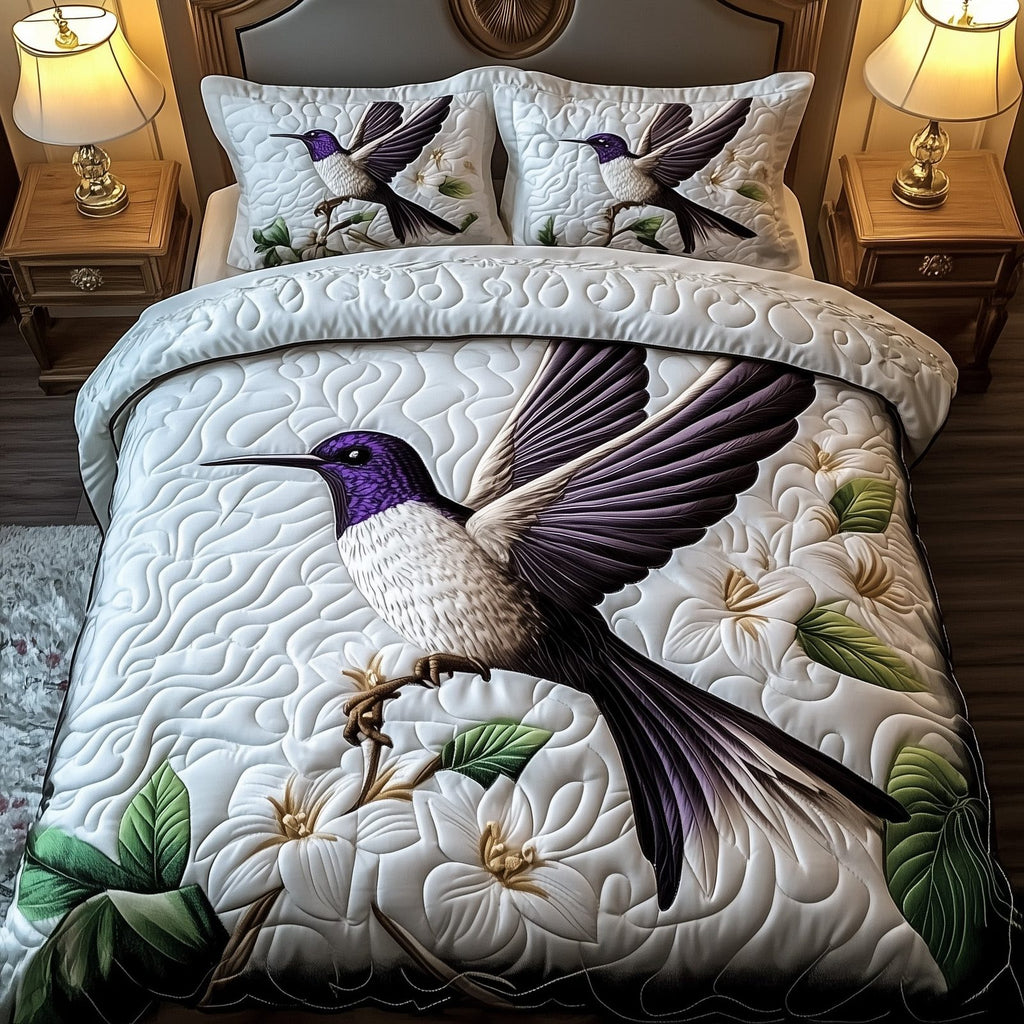 Hummingbird Bloom Symphony quilted 3-piece bedding set on a made bed with two matching pillow shams