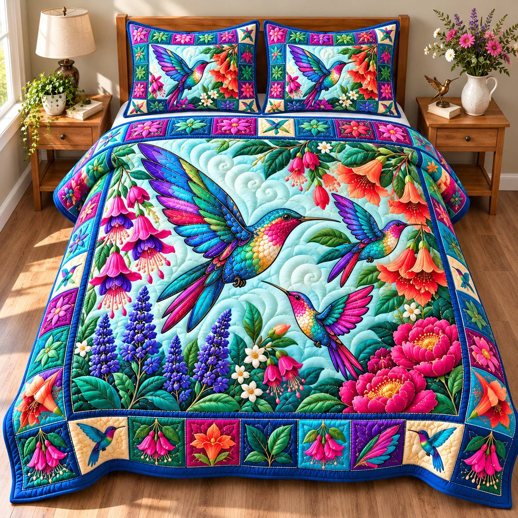 Hummingbird Blossom Haven quilted 3-piece bedding set on a made bed with two matching pillow shams