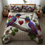 Hummingbird Embrace Heart quilted 3-piece bedding set on a made bed with two matching pillow shams