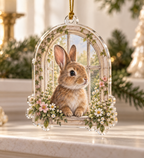 Custom-shaped clear acrylic ornament with a rabbit peeking through a flower-framed arched garden window and gold cord.
