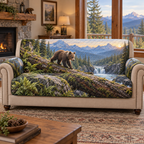 A quilted sofa protector printed with a bear cub crossing a fallen log above an alpine gorge and waterfall.