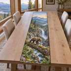 A rectangular table runner printed with a bear cub crossing a fallen log above an alpine gorge and waterfall.
