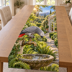 An African grey parrot leans toward water droplets above a stone birdbath, with fern beds, conservatory path and distant sunlit hills.