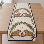 One ivory quilted table runner with four printed capybaras, fir orange cinnamon arches and two cranberry lanterns, navy binding and cream reverse corner