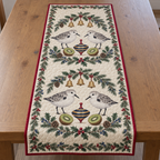 One ivory quilted table runner with four sanderlings navy toy spinning tops kiwi halves fir juniper holly ochre bells cranberry binding sewn quilting