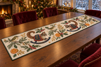 Rifleman Orange Rocking Sugar Glider quilted cotton table runner four printed green birds two brown rocking sugar gliders oranges green binding sewn channels flat on walnut table in warm Christmas dining room.