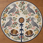 Four illustrated ash-gray kagus with swept-back crests and red-orange bills and legs frame two brown toy rocking echidnas with cranberry legs, ochre saddles and navy rockers, quince halves, cedar, holly, mistletoe and ochre snowflakes on ivory with navy binding. Flat printed Christmas artwork. Includes one circular tree skirt with center opening and tie closure. Visible sewn quilting and continuous radial opening.