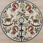 Four illustrated chestnut-and-white Jacobin pigeons with circular feather hoods, pale faces and pink feet frame two brown toy rocking dik-diks with tiny horns, large ears, gray-brown faces, navy saddles with ochre botanical detail and navy rockers, apple halves, cedar, holly, mistletoe and ochre snowflakes on ivory with navy binding. Flat printed Christmas artwork. Includes one circular tree skirt with center opening and tie closure. Visible sewn quilting and continuous radial opening.
