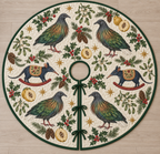 Four illustrated Nicobar pigeons with gray heads, green-copper neck hackles, green wings, white tails and red legs frame two navy toy rocking bandicoots with pointed snouts, small ears, ochre saddles and cranberry rockers, quince halves, cedar, holly, mistletoe and ochre stars on ivory with forest-green binding. Flat printed Christmas artwork. Includes one circular tree skirt with center opening and tie closure. Visible sewn quilting and continuous radial opening.